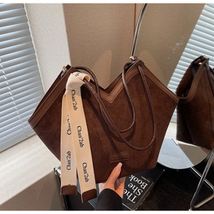 Detailed macro view of retro coffee brown suede tote bag with brand ribbon and leather tag
