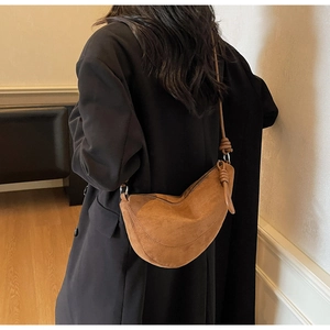 Close-up of brown suede crescent bag featuring unique knotted shoulder strap detail