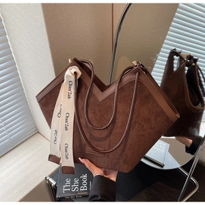 Detailed close-up of dark brown suede tote bag with V-shaped opening and decorative ribbon