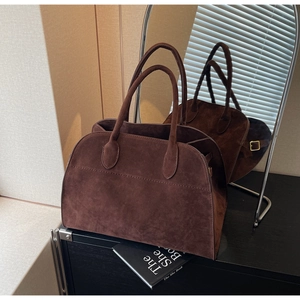 Gros plan d'un cabas en daim marron avec coutures fines et boucle latérale en métal