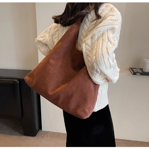 Detailed back view of a large brown suede tote bag styled in a minimalist interior setting