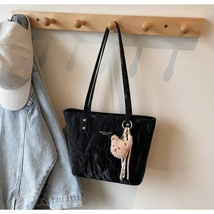Close-up of black crinkle leather tote bag with gold lettering and cute bear charm
