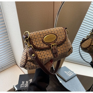 Close-up of vintage houndstooth crossbody bag with leather trim and gold metal logo plate