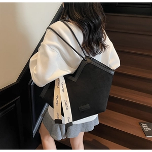 Close-up of black matte tote bag with decorative beige straps and leather piping detail