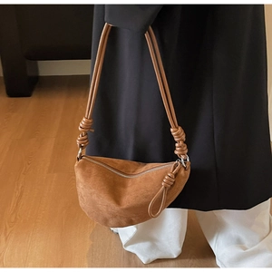 Detail showing brown suede crescent bag with unique knot shoulder strap and zipper