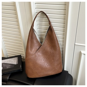 Dettaglio della borsa tote marrone caramello con texture in pelle plissettata e apertura a V