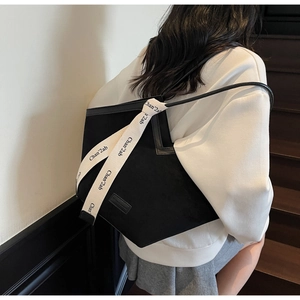 Detail of black matte tote bag with decorative beige ribbon and sleek shoulder straps
