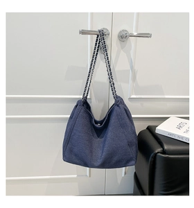 Detail der dunkelblauen Denim-Hobo-Tasche mit Silberkette an einem Türgriff hängend