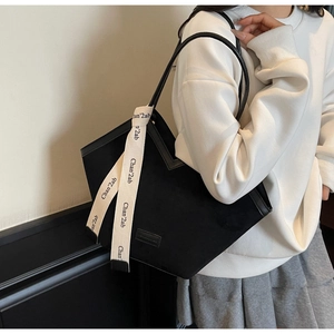 Detail of black matte tote bag featuring long printed ribbon on the handle