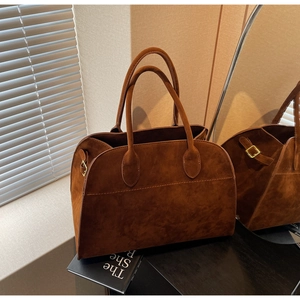 Gros plan du sac cabas vintage en daim marron avec doubles anses sur une table en bois
