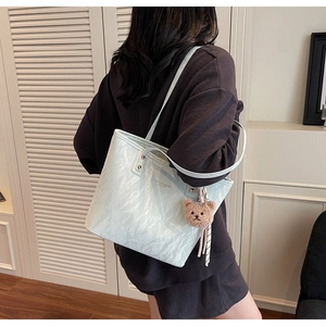 Detail of light blue tote bag with marble texture and a brown plush bear charm