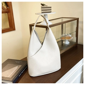 Elegante borsa tote in pelle crema con tasca a V su un bancone in legno rustico