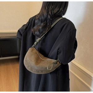 Detail view of the brown suede dumpling bag with decorative green knotted shoulder strap