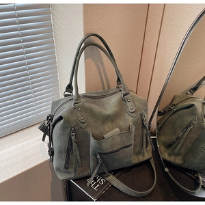 Detail of dark green matte leather tote bag with multi-pockets and smooth top handles
