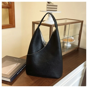 Dettaglio borsa hobo in pelle nera con texture stropicciata e tasca frontale asimmetrica