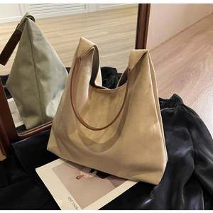 Detail view of a minimalist beige hobo bag with a dark brown round handle on silk fabric
