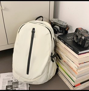 Detailed view of white minimalist backpack with vertical black zipper and books