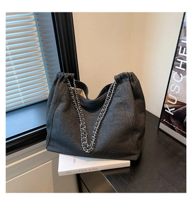 Detailansicht der dunkelgrauen Denim-Tragetasche mit Kordelzug und silbernen Kettenriemen