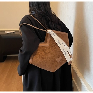 Detail view of brown faux suede tote bag featuring unique geometric V-cut and logo strap