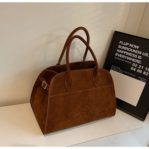 Gros plan sur un sac cabas en daim marron avec coutures fines et boucle en métal doré