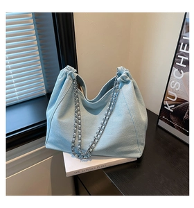 Detail der hellblauen Denim-Tragetasche mit Kettenriemen und elegantem Plissee-Verschluss