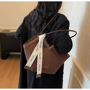 Detail of vintage brown suede tote bag featuring a decorative beige woven brand ribbon