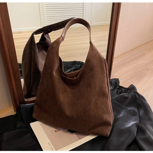 Macro detail of dark brown suede hobo bag with matte texture and magnetic snap closure