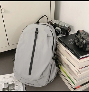 Detail view of the light grey travel backpack with a vertical front zipper pocket