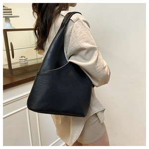 Vista laterale della grande borsa hobo in ecopelle nera con cuciture su una modella