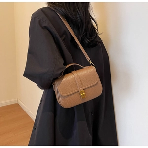 Detail of a brown lychee pattern leather handbag featuring a gold metal buckle closure