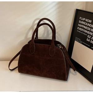 Gros plan sur un sac docteur vintage en daim marron foncé avec deux poignées et fermeture métal