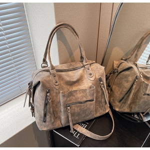 Close-up of vintage taupe Boston bag detailing the worn leather texture and side zipper