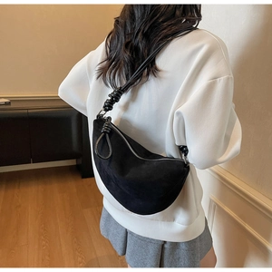 Close-up of black suede hobo bag with unique knotted strap and silver zipper detail