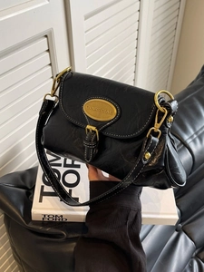 Vintage black glossy leather crossbody bag with gold buckle and slim strap on display