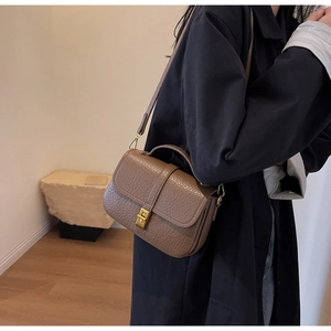 Detail of tan pebble leather vintage square bag featuring gold clasp and sleek handle