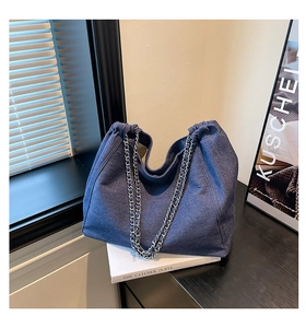 Detail der tiefblauen Denim-Tasche mit Kordelzugverschluss und silbernen Kettenriemen