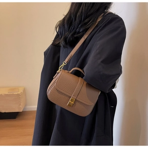 Detail of a brown lychee pattern leather handbag with gold lock on a wool coat