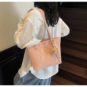 Detail of light pink wrinkled glossy tote bag with fashion text and cute bear charm