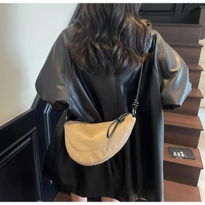 Detail of light khaki suede crescent bag with knot leather strap on a model's back