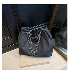 Detailansicht der Hobo-Tasche aus dunklem Denim mit Silberkette und plissierter Stoffstruktur