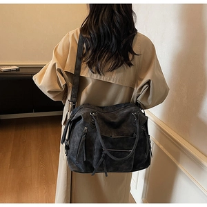Detail of dark grey frosted leather tote bag with tassels and multiple zipper pockets
