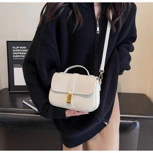 Close-up of cream textured faux leather bag with gold clasp shown on a model