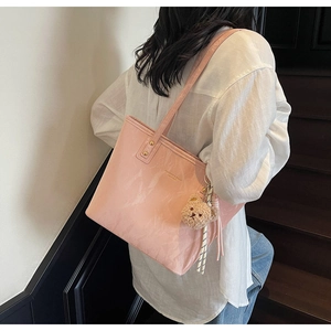 Detail of pink marble pattern tote bag featuring a teddy bear charm and logo print