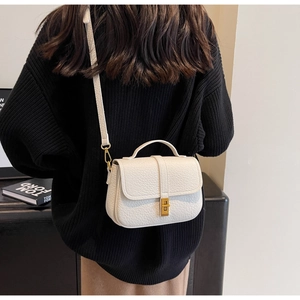 Detail of cream white lychee leather saddle bag with gold buckle on casual outfit