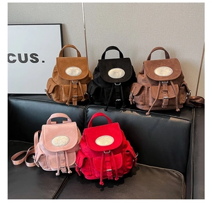 Mini sacs à dos en daim de cinq couleurs présentés sur un canapé en cuir noir