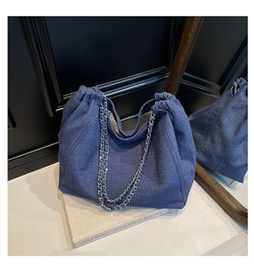 Detailansicht der dunkelblauen Denim-Tragetasche mit silbernem Kettenriemen und Kordelzug