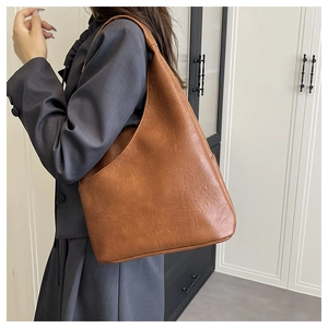 Borsa hobo vintage marrone in ecopelle opaca su modella con ampia tracolla