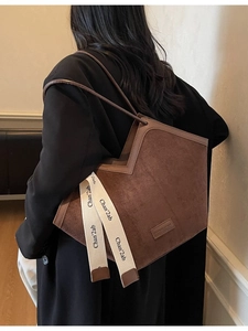 Brown frosted suede tote bag with dual shoulder straps and ribbon detail shown on model