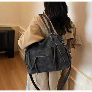 Detailed view of dark grey matte tote with multiple zipper pockets and tassel accents