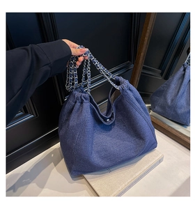 Detail einer dunkelblauen Denim-Einkaufstasche mit silbernen Ketten und Kordelzug